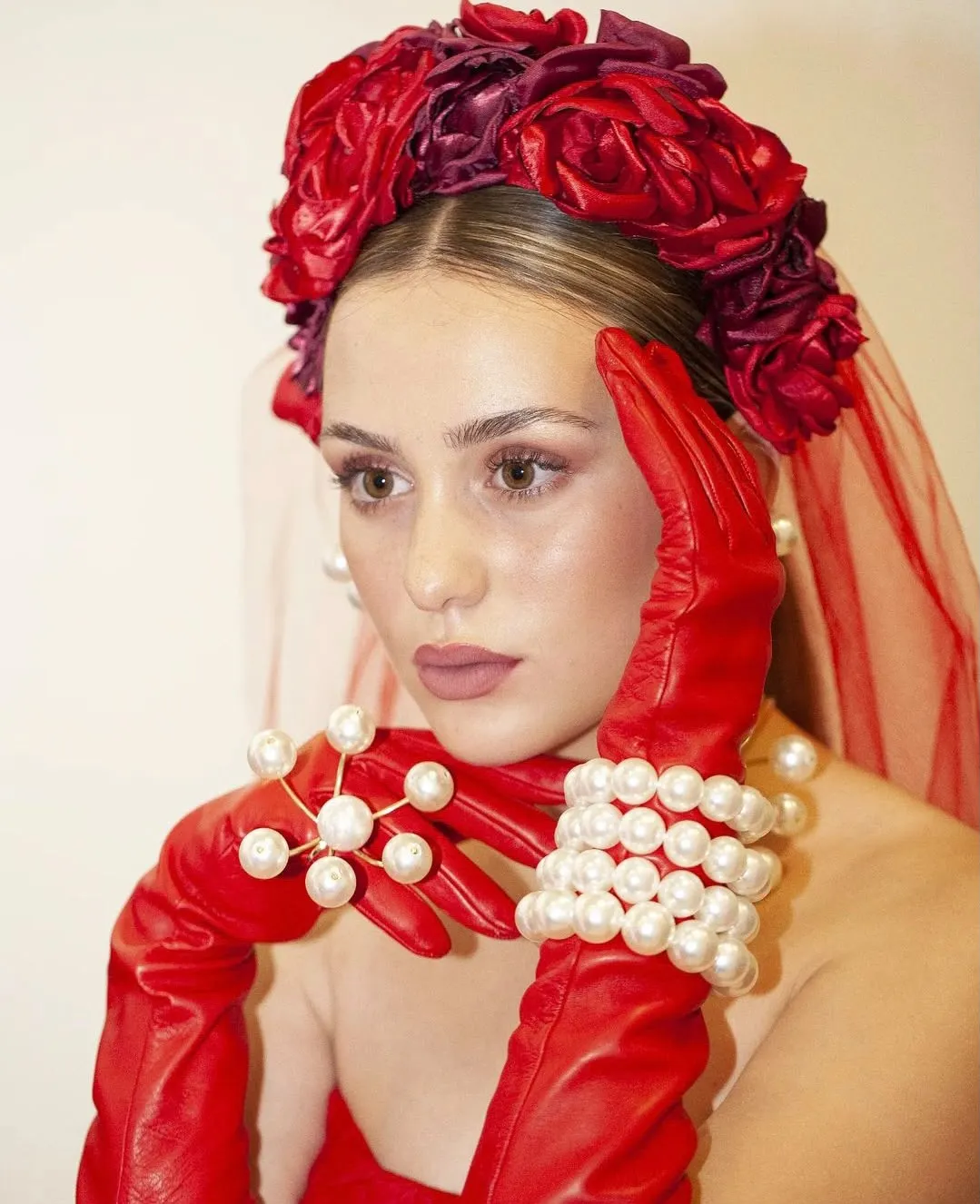 Maquillaje creativo editorial con tocado rojo, guantes y perlas