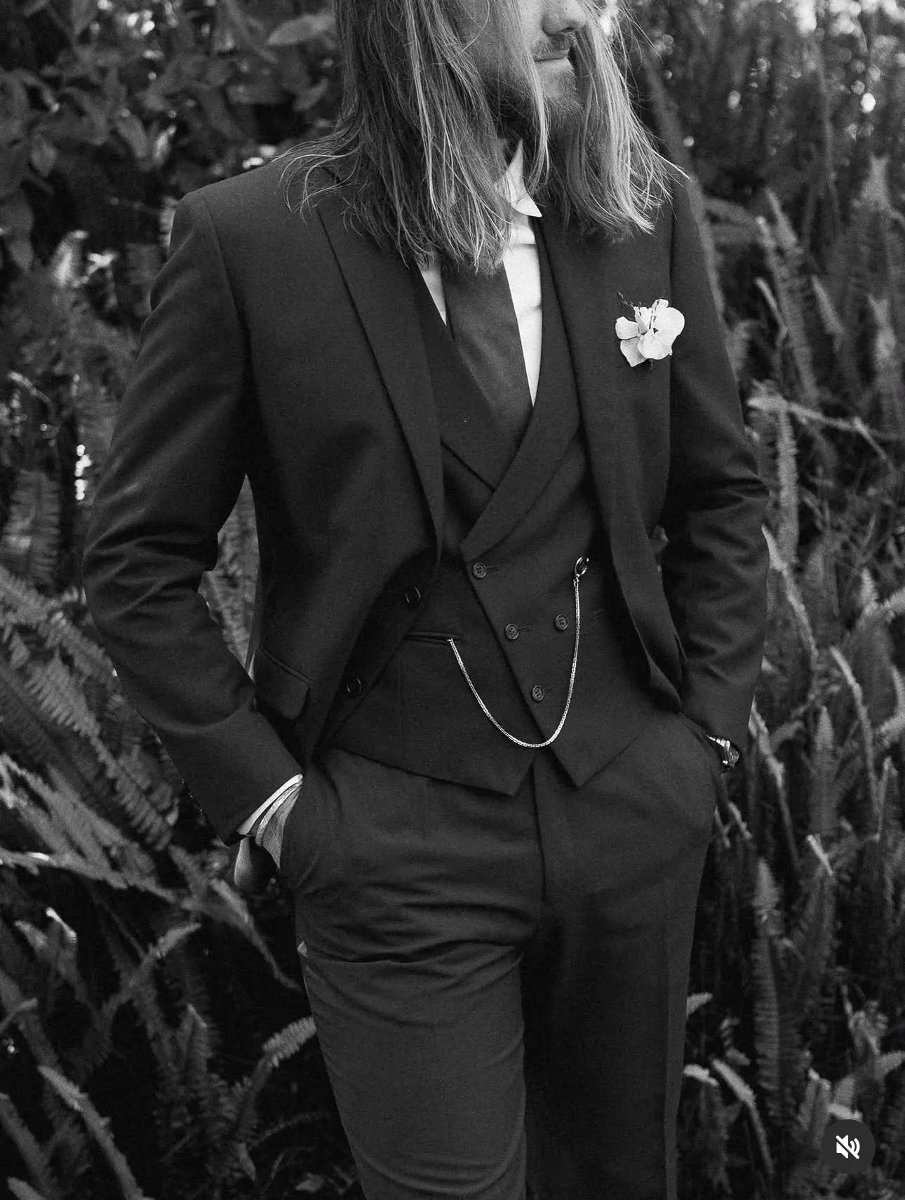 Novio con traje oscuro y flor en la solapa