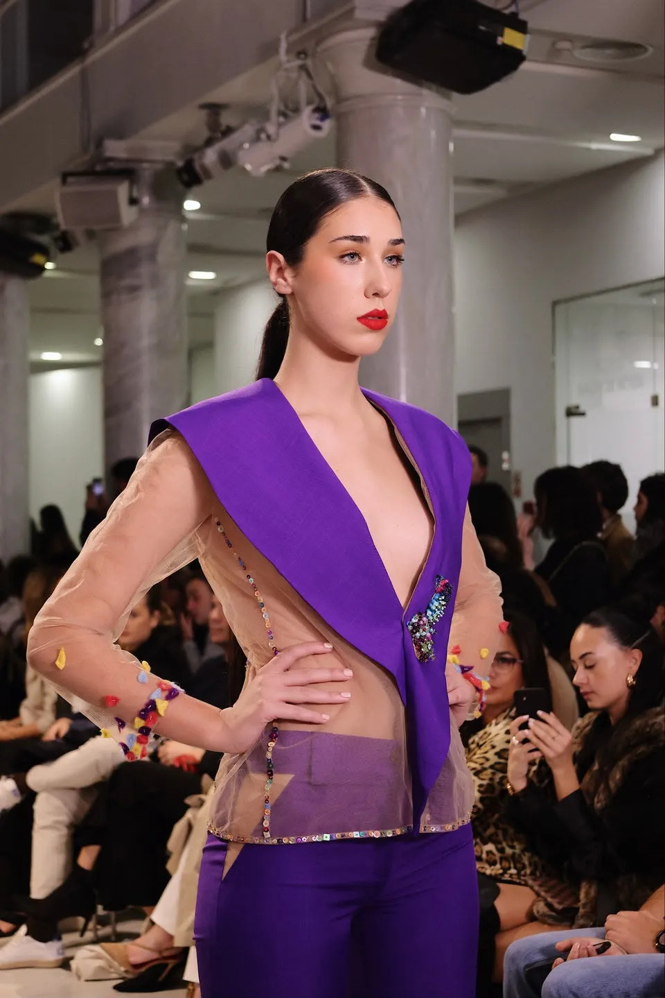 Modelo con maquillaje y diseño violeta en una pasarela