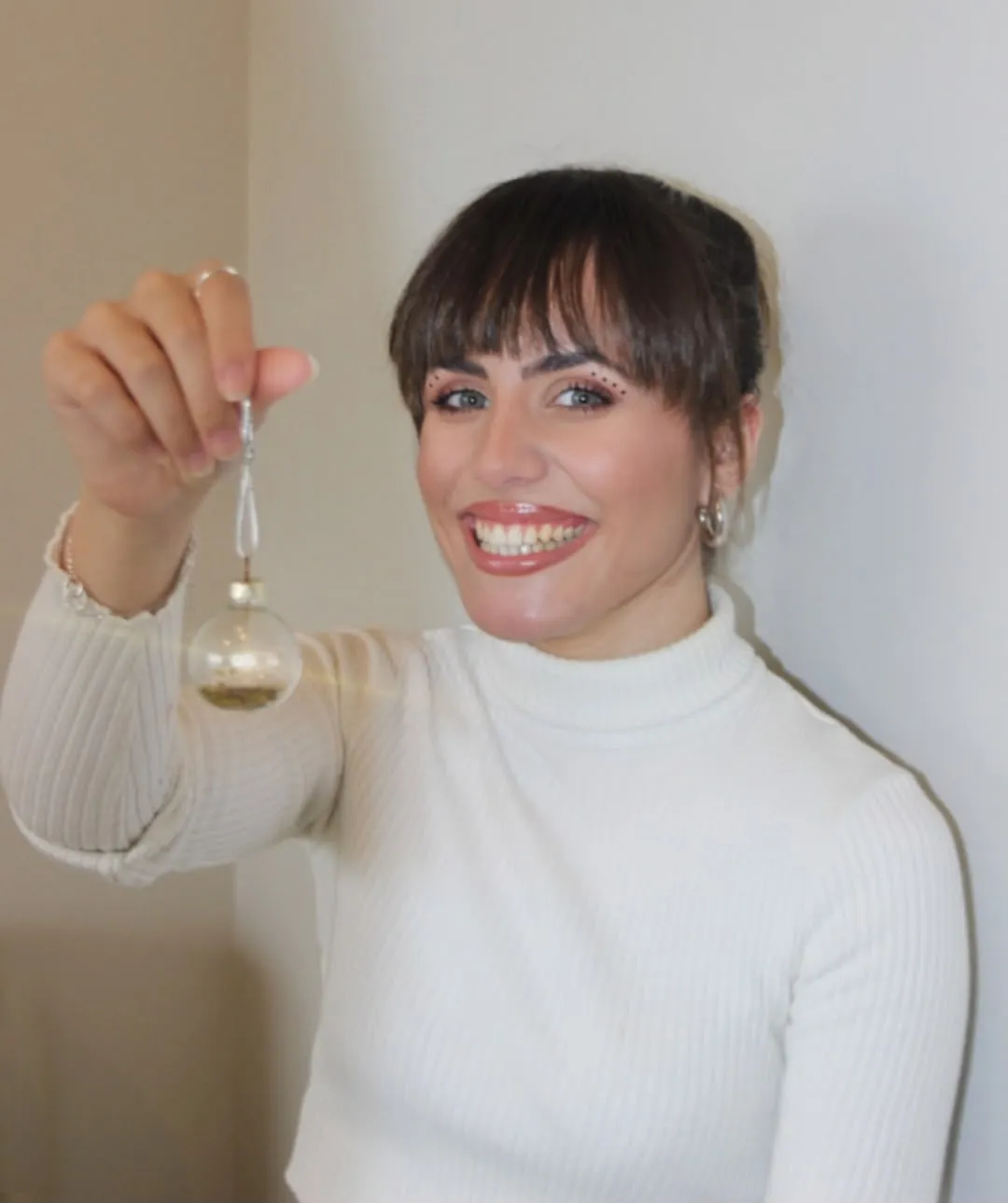 Retrato de una mujer mostrando un adorno de cristal en un interior